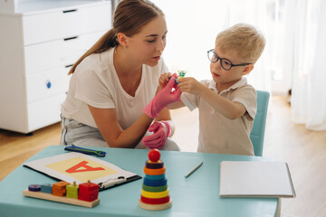 By the blue table. Speech therapist is with young boy indoors