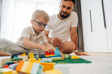 Having a great weekend. Father is playing in the room with his little son with construction sets