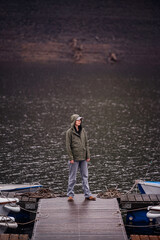 Person Standing Alone on Rainy Dock by Lake and Boats
