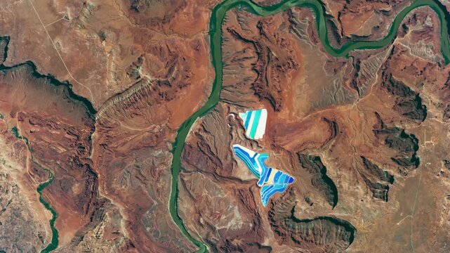 Aerial shot of potash ponds, red rocks, deserted dry area with canyon of a river. Camera is moving backward. Animation based on image by NASA