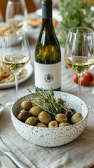 Still life with bottle of white wine, two glasses, and bowl of olives on marble, creating an elegant Mediterranean dining or tasting invitation.