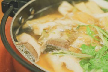 Japanese hot pot dish made with yellowtail fish, udon noodles, mizuna greens, and green onions