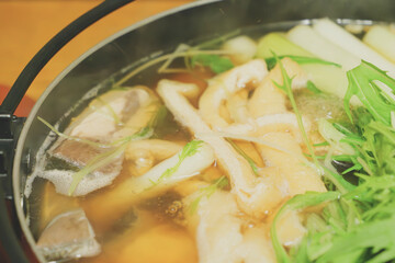 Japanese hot pot dish made with yellowtail fish, udon noodles, mizuna greens, and green onions