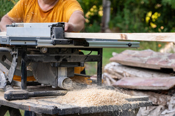 A worker cutting wood with a circular saw. Working with wood