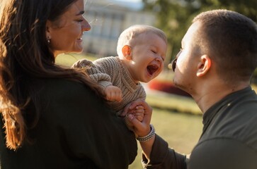happy young caucasian family with baby boy having fun in a park.