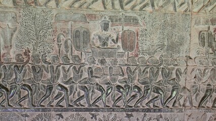 Angkor Wat, Cambodia - 3 July 2025. A carved royal procession shows a king seated under parasols, borne by attendants in motion, framed by trees and ceremonial objects.