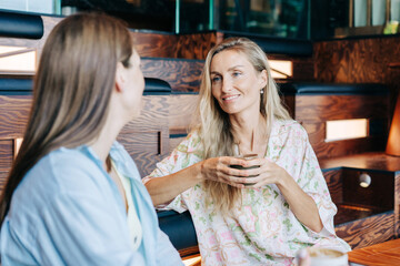 Two women are talking while sitting in a cafe.