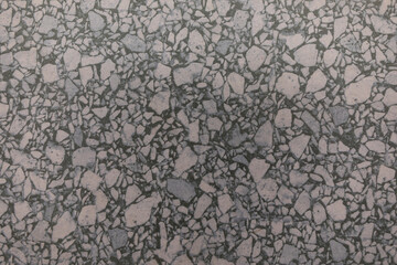 Unique textured surface displaying a mix of gray and pink stones at an urban location during daylight hours