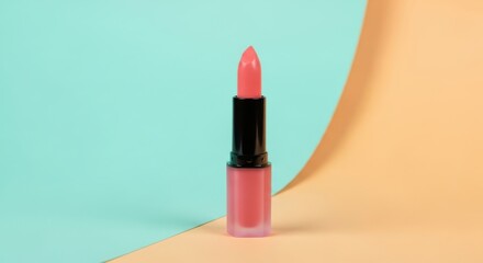 A vibrant pink lipstick stands out against a split pastel background of blue and orange