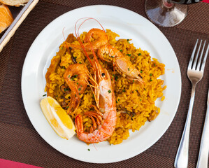 Paella made of rice and different seafood served in plate with other table appointments