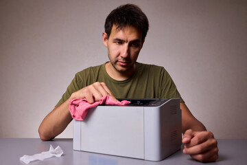 A focused man cleaning a device with a cloth for proper maintenance and cleanliness