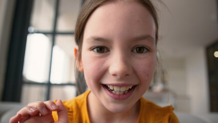 Webcam POV carefree joyful smiling Caucasian schoolgirl girl daughter zoom screen device AR kid using mobile phone touchscreen slide fingers screen at home preteen child typing smartphone gadget tech