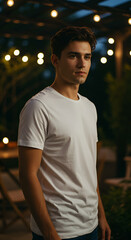 Fototapeta premium A young man in a white t-shirt outdoors at night