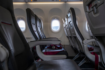 Empty airplane seats and interior layout in narrow-body aircraft, viewed in soft lighting with visible windows and upholstery details, modern commercial aviation concept.