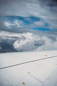 Airplane wing and engine flying over dense cloudscape under a dramatic sky, powerful visual of transportation in upper atmosphere and connection across distances.