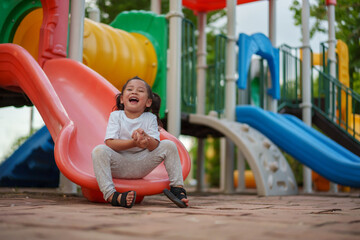 happy toddler baby girl sliding and playing at playground