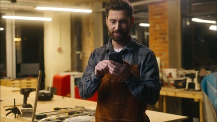 Glad smiling Caucasian handyman technician designer male man carpenter guy use mobile phone in workshop employer wood master showing green screen apps advertisement small business touchscreen display