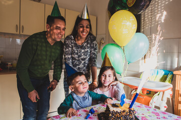 Family celebrating child's third birthday with cake and sparkler