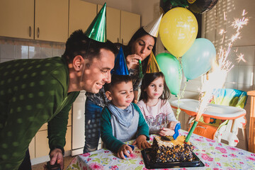 Family celebrating kid birthday at home with cake and balloons