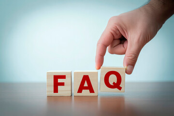 FAQ Wooden Blocks Concept – Frequently Asked Questions Symbol with Hand on Blue Background