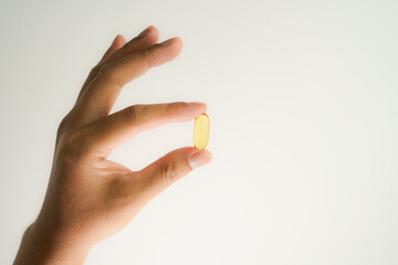 Male hand holding Fish oil capsules with omega 3, omega 9, vitamin D, vitamin E, Cod liver oil