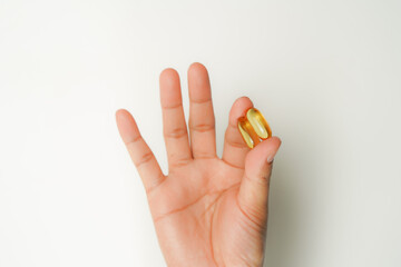 Male hand holding soft gels, Fish oil capsules, omega 3, omega 9, vitamin D, vitamin E, supplements