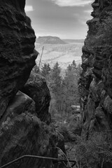 View into a rocky gorge with a wooded valley and hills in the background