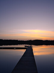 A wooden walkway in Sweden leads into a quiet lake at sunset. Scandinavia