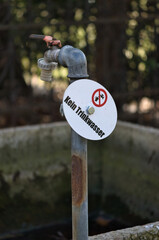 Old outdoor faucet with warning sign “Not for drinking water”.