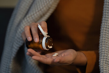 Self-Care Routine. Woman pouring pills from medicine bottle into hand.
