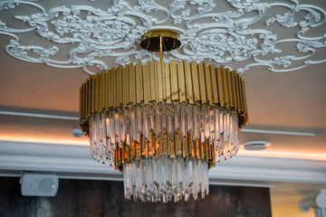 The Elegant Golden Chandelier, with its exquisite Crystal Accents, enhances a Luxurious Setting,...