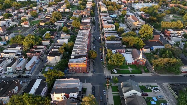Slow drone flight over Main Street of American town with townhouses and historic row homes. Sunset time in Camden, New Jersey. Summer day in America. Roofing flight. Quiet scene.