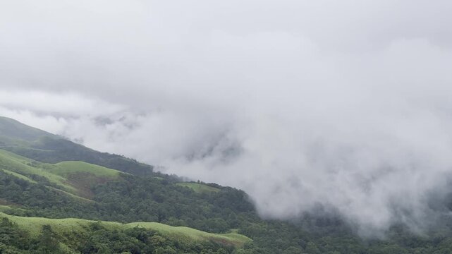 Rolling green mountains of Devarmane, Malnad, Karnataka during monsoon. Rain clouds sweep swiftly overhead, capturing the serene and dramatic beauty of the Western Ghats.