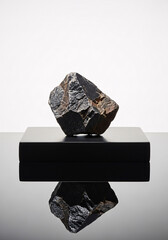 Striking geological specimen showcased on sleek black pedestal against a clean white backdrop, its raw texture and natural beauty captivating.