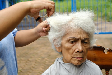 Portrait of an elderly woman getting her hair cut by a carer.