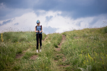 Obraz premium Young hiker pausing on a meadow path under cloudy sky