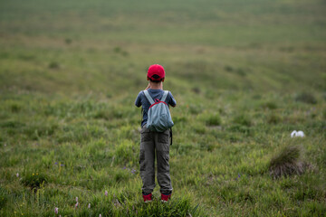Youngster hiking alone in vast grassland taking pictures
