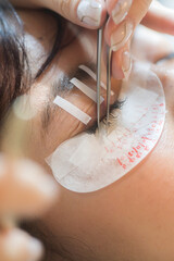 Young southeast asian woman enjoying eyelashes extension procedure in beauty salon. professional...