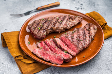 Tender flat iron steak, grilled to enhance its natural flavors and tenderness. grey background. top...