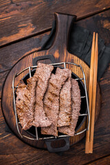 Flavorful yakiniku with juicy wagyu beef slices cooked right at the table. wooden background. top view
