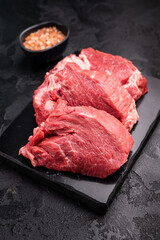 Raw beef boneless shank shin presented with herbs and spices, inspiring bold flavors and unique recipes for adventurous home cooks. black background. top view