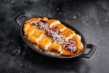 Crunchy Japanese cutlet katsu, seasoned to perfection and served with a side of rice and sauce. black background. top view