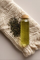 Light beige knitted fabric draped over a light beige surface, with loose dried green tea leaves and a small clear glass bottle of tea liquid