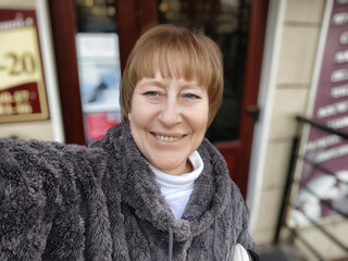 Middle-aged woman takes selfie outside a lifestyle blog location during daytime