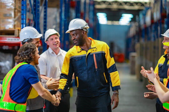 Male industrial worker receives applause and recognition from multicultural team. Great for HR campaigns, teamwork, and leadership visuals.