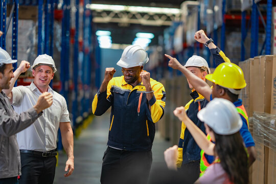Centered African-American employee being recognized by team members in warehouse. Inspires themes of motivation, leadership, and success.