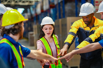 Team huddle moment among logistics professionals in a warehouse. Stacked hands signify readiness,...