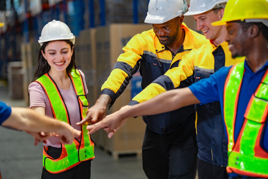 Dedicated staff in warehouse join hands to begin the day with a shared goal. A powerful symbol of trust, inclusion, and cooperation for HR campaigns or business success stories.