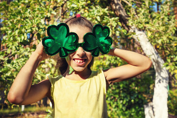 Little girl with big, funny sunglasses enjoys the sun. The girl in the garden in summer....