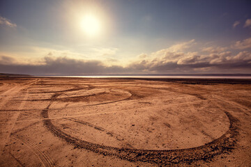 Car tracks in the sand. Salt marsh beach at sunset